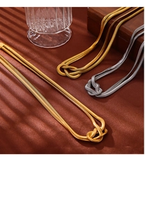 Detail of knotted gold and silver snake chain necklaces on silk background