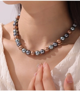 Detailed view of high-luster grey, blue, and bronze pearl necklace on female model