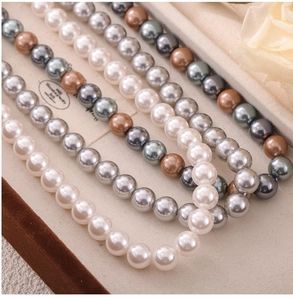 Detailed view of multicolor shell pearl necklace with white and grey beads in a jewelry box