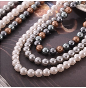 Detail of colorful round pearl necklaces in white, grey, and brown with high-gloss finish