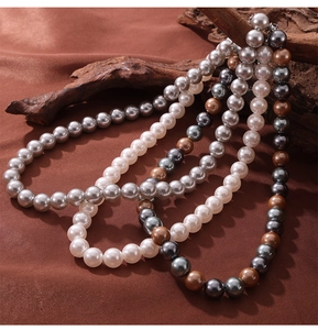 Detail of round shell pearl necklaces in white, grey, and champagne on dark velvet