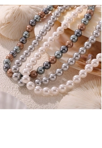 Detailed view of multi-color pearl necklaces in white, grey, and bronze tones