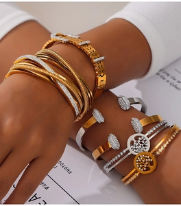 Détail de bracelets superposés en plaqué or et argent avec breloque arbre de vie