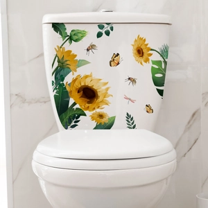 Détail de stickers tournesol et papillon sur un réservoir de toilette en céramique blanche