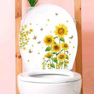 Détail de stickers autocollants tournesols et papillons sur un abattant de WC blanc