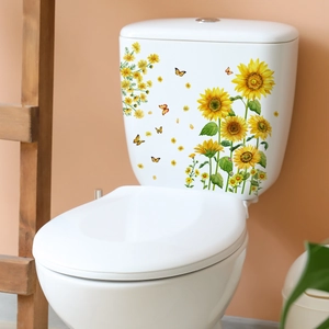 Détail des stickers tournesol et papillon imperméables sur un réservoir de WC blanc