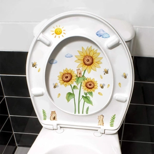 Détail de stickers muraux tournesol et hamster posés sur un abattant de WC blanc