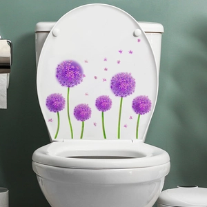 Détail d'autocollants de fleurs d'allium violettes sur un abattant de WC en céramique blanc
