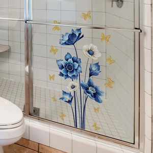 Detalle de adhesivos de flores azules y mariposas doradas para puerta de vidrio de baño