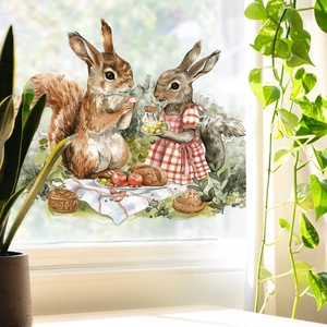 Close-up of watercolor squirrel picnic window sticker on glass with green plants nearby