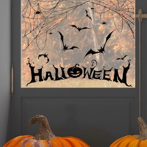 Close-up of Halloween window decals featuring black bats and pumpkins on glass
