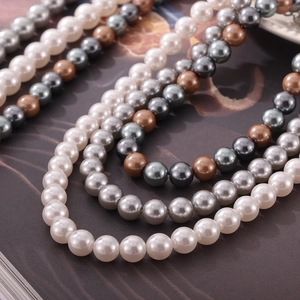 Fashion colorful round pearl necklaces in white, grey, and bronze on textured background