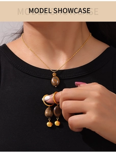 Detailed view of model wearing gold tiger eye necklace and earrings with Lucky charm