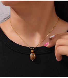 Close-up of vintage tiger eye stone pendant necklace on a model with gold chain detail