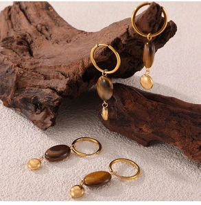 Detail of vintage gold tiger eye earrings with Lucky charm on rustic wood
