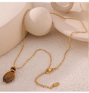 Detailed shot of tiger eye pendant on a gold bead chain with S.steel hallmark