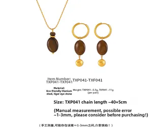 Detail of tiger eye stone pendant and lucky engraving on gold plated titanium jewelry set