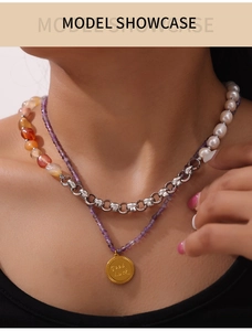 Detail of double-layer necklace with natural purple stones, pearls and Good Luck pendant