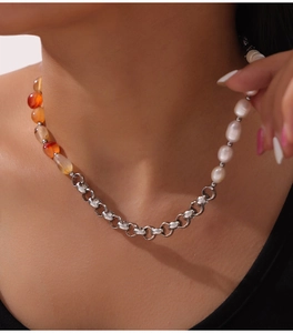 Detail of beaded necklace with white pearls, orange natural stones and gold-plated chain