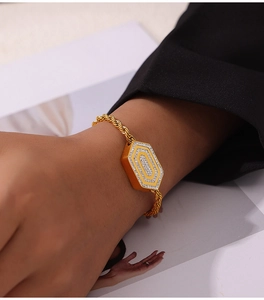 Detailansicht eines goldenen Sechseck-Anhängers mit Zirkonia am Kordelarmband am Handgelenk