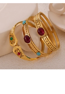 Détail de bracelets dorés avec motifs évidés complexes et pierres précieuses colorées