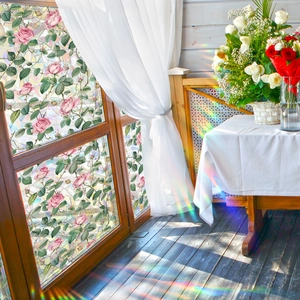 Floral stained glass window film with pink roses and rainbow light refraction on wood door