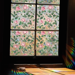 Rainbow light refraction from floral window film onto a wooden table surface