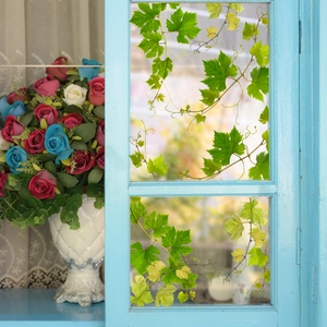 Green vine window sticker on light blue frame with elegant floral vase and lace background