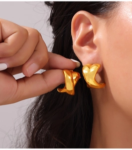 Gros plan de boucles d'oreilles créoles dorées géométriques avec finition polie miroir