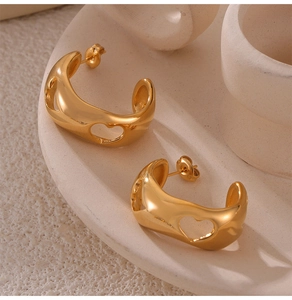 Détail de boucles d'oreilles créoles dorées avec motifs ajourés en forme de cœur