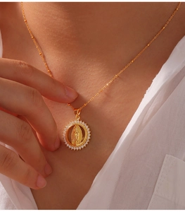 Detailed shot of golden pendant featuring Virgin Mary relief and white cubic zirconia