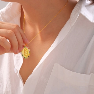 Gold oval religious pendant necklace with colorful zircons worn on a model for a luxury look