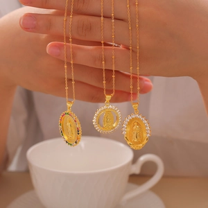 Golden Virgin Mary pendants with colorful zircons on delicate bead chains held by hand