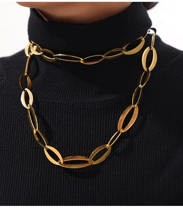 Detalle de collar de cadena cubana dorada a capas sobre un jersey de punto negro