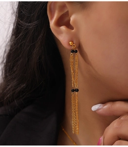 Close-up of long gold tassel earrings with black agate beads on a professional model