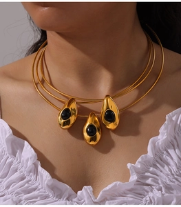 Détail d'un collier à trois couches en or avec trois pendentifs goutte d'eau noirs