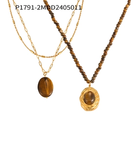 Détail de colliers en titane doré vintage avec pendentifs ovales en œil de tigre
