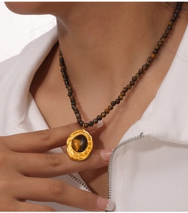 Détail du pendentif ovale en œil de tigre avec cadre doré et chaîne à billes marron
