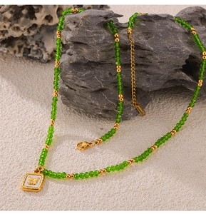 Nahaufnahme der grünen Kristallperlenkette mit einem goldenen Schmetterlingsanhänger