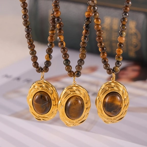Trois colliers avec pendentifs ovales en œil de tigre sur fond vintage chic
