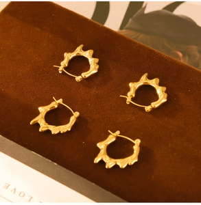 Détail de boucles d'oreilles dorées en C avec texture de lave liquide sur support en velours
