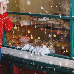 Autocollants de Noël rouges et dorés avec flocons et étoiles sur la vitre d'une boulangerie