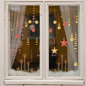 Gros plan de boules de Noël rouges et dorées et stickers étoiles sur une fenêtre blanche