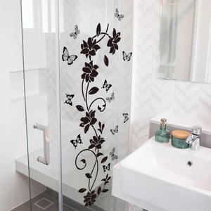 Detailed close-up of black floral and butterfly self-adhesive wall stickers on bathroom glass