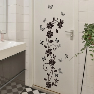 Detail of black floral vine and butterfly wall decals on a modern white bathroom door