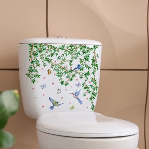 Floral wall decal with birds and green leaves applied to a white ceramic toilet tank