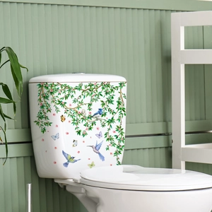 Detail showing self-adhesive toilet stickers with green leaves and colorful birds on white ceramic