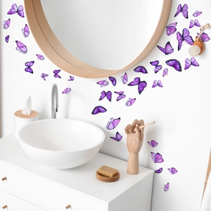 Détail de stickers muraux papillons violets disposés autour d'un miroir de salle de bain