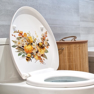 Dettaglio dell'adesivo murale con api e fiori su un coperchio del WC bianco