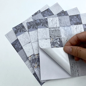 Detail showing self-adhesive backing of retro grey and white marble pattern wall tiles